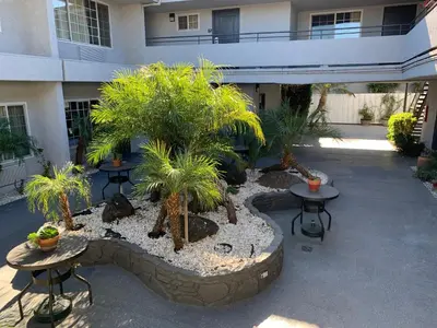 a courtyard with tables and palm trees in front of a building at Skyways Hotel in Los Angeles