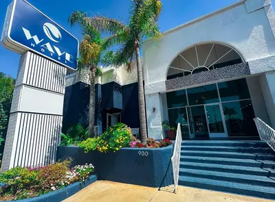 a sign in front of a building with a palm tree at Wave Hotel Manhattan Beach in Manhattan Beach