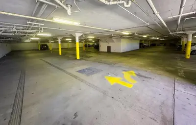 an empty parking garage with a yellow arrow painted on the floor at Wave Hotel Manhattan Beach in Manhattan Beach