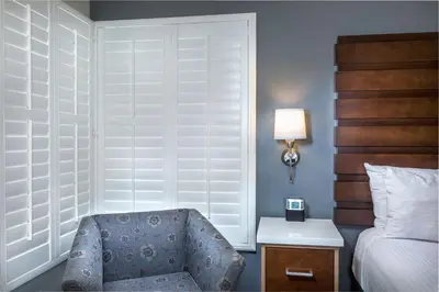 a bedroom with a chair and a bed and a lamp at Desert Palms Hotel & Suites Anaheim Resort in Anaheim