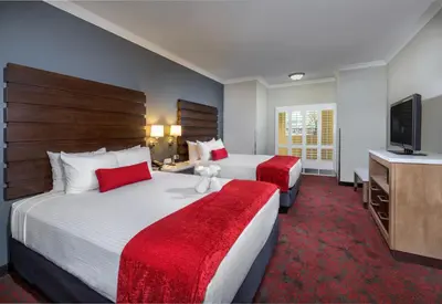 a hotel room with two beds and a flat screen tv at Desert Palms Hotel & Suites Anaheim Resort in Anaheim