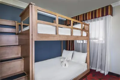 a bedroom with a bunk bed with white sheets at Desert Palms Hotel & Suites Anaheim Resort in Anaheim