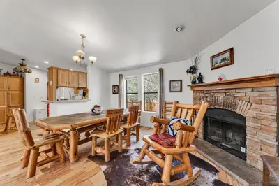 a dining room with a table and chairs and a fireplace at Country Club Chalet in Big Bear City