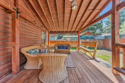 a cabin with a deck with wicker furniture at Country Club Chalet in Big Bear City