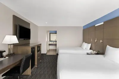 a hotel room with two beds and a desk at Travelodge Inn & Suites by Wyndham Anaheim on Disneyland Dr in Anaheim