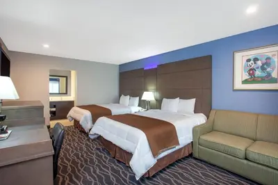 a hotel room with two beds and a couch at Travelodge Inn & Suites by Wyndham Anaheim on Disneyland Dr in Anaheim