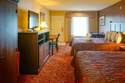 a hotel room with two beds and a flat screen tv at Castle Inn and Suites Anaheim in Anaheim