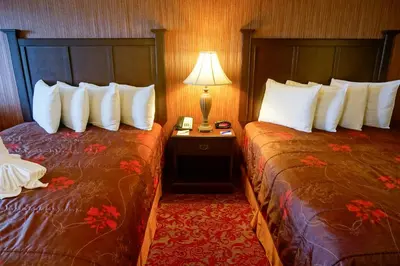a hotel room with two beds and a table with a lamp at Castle Inn and Suites Anaheim in Anaheim