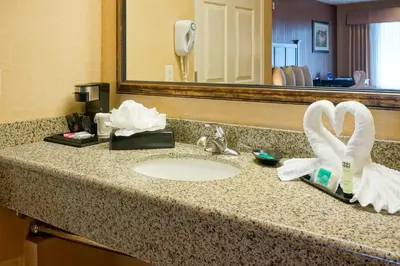 a bathroom counter with a sink with towels and a mirror at Castle Inn and Suites Anaheim in Anaheim
