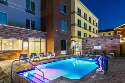 a swimming pool with chairs and a building at Fairfield Inn & Suites Ontario Rancho Cucamonga in Rancho Cucamonga