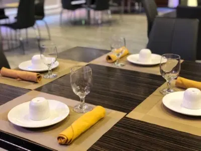 a table with white plates and wine glasses on it at Holiday Inn El Monte - Los Angeles by IHG in El Monte