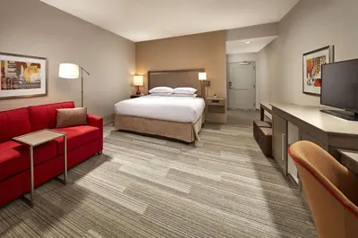 a hotel room with a bed and a red couch at Hampton Inn Long Beach Airport, Ca in Long Beach