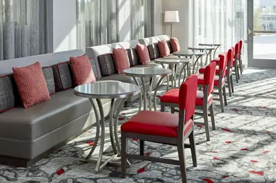 a row of tables and chairs with red cushions at Hampton Inn Long Beach Airport, Ca in Long Beach