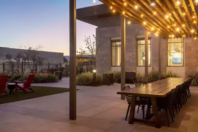 a patio with a wooden table and chairs and lights at Homewood Suites By Hilton Long Beach Airport in Long Beach
