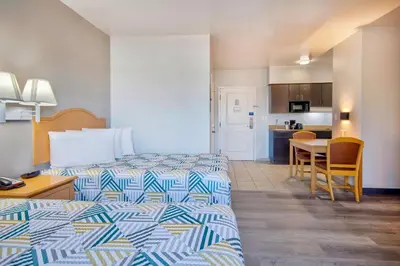 a hotel room with two beds and a table and a kitchen at Studio 6-Bakersfield, CA in Bakersfield