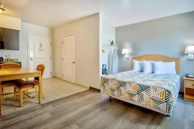 a bedroom with a bed and a table and a kitchen at Studio 6-Bakersfield, CA in Bakersfield