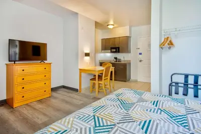a bedroom with a bed and a television and a kitchen at Studio 6-Bakersfield, CA in Bakersfield