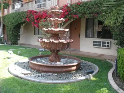 a fountain in the grass in front of a building at Garden Inn and Suites Glendora in Glendora