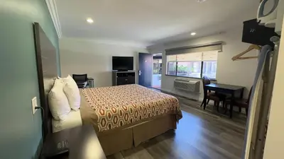 a hotel room with a bed and a dining room at Garden Inn and Suites Glendora in Glendora