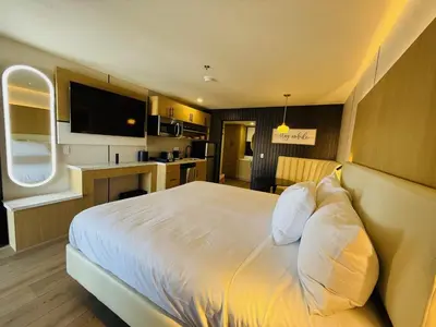 a bedroom with a white bed and a kitchen at MainStay Suites Victorville - Hesperia in Victorville