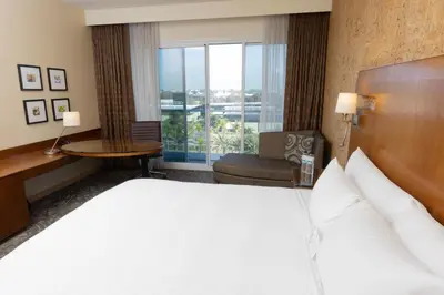 a hotel room with a bed and a chair and a window at Miyako Hybrid Hotel Torrance in Torrance