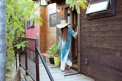 a woman in a hat standing on a porch at Caravan Outpost in Ojai