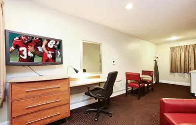 a hotel room with a tv and a desk and chairs at Red Roof Inn Santa Ana in Santa Ana