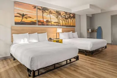 two beds in a hotel room with palm trees at Days Inn & Suites by Wyndham Artesia in Artesia