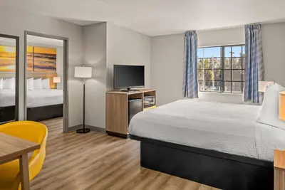 a hotel room with a bed and a flat screen tv at Days Inn & Suites by Wyndham Artesia in Artesia