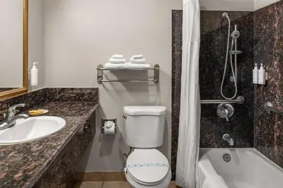 a bathroom with a toilet and a sink and a tub at Days Inn & Suites by Wyndham Artesia in Artesia