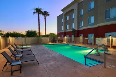 a swimming pool with chairs and a building at Hampton Inn & Suites Ridgecrest in Ridgecrest