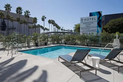 a swimming pool with two chairs and a hotel sign at H Hotel Los Angeles, Curio Collection By Hilton in Los Angeles