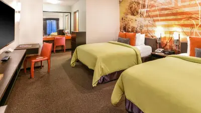 a hotel room with two beds and a dining room at The Tangerine - a Burbank Hotel in Burbank