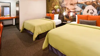 a hotel room with two beds and a painting on the wall at The Tangerine - a Burbank Hotel in Burbank