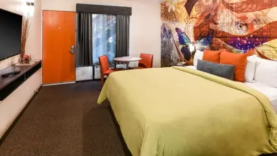 a hotel room with a large bed and a television at The Tangerine - a Burbank Hotel in Burbank