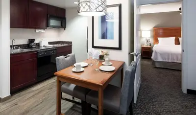 a hotel room with a table and a kitchen and a bed at Homewood Suites by Hilton Agoura Hills in Agoura Hills