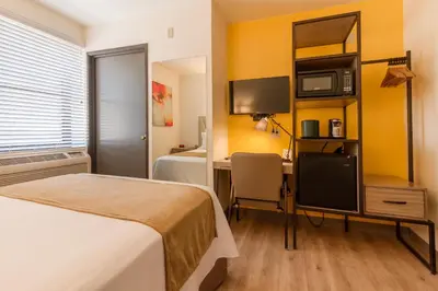 a hotel room with a bed and a desk with a tv at Kawada Hotel in Los Angeles