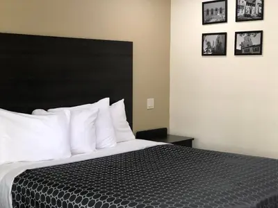 a bedroom with a bed with a black headboard and white pillows at Simply Home Inn & Suites - Riverside in Riverside