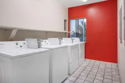 a kitchen with white washing machines and a red wall at Ramada by Wyndham Bakersfield in Bakersfield