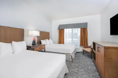 a hotel room with two beds and a flat screen tv at Ramada by Wyndham Bakersfield in Bakersfield