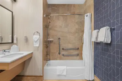 a bathroom with a shower and a tub and a sink at Spark by Hilton Bakersfield Central in Bakersfield