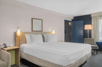 a hotel room with a large bed and a chair at Spark by Hilton Bakersfield Central in Bakersfield
