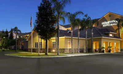 a large yellow building with palm trees in front of it at Homewood Suites Bakersfield in Bakersfield