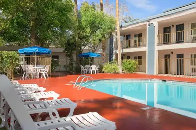 a swimming pool with white chairs and a hotel at Travelodge by Wyndham Bakersfield in Bakersfield