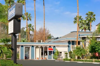 a building with palm trees in front of it at Travelodge by Wyndham Bakersfield in Bakersfield