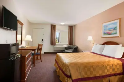 a hotel room with a bed and a desk at Travelodge by Wyndham Bakersfield in Bakersfield