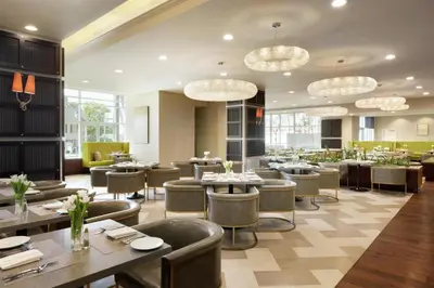 a restaurant with tables and chairs and chandeliers at Embassy Suites Los Angeles Glendale in Glendale
