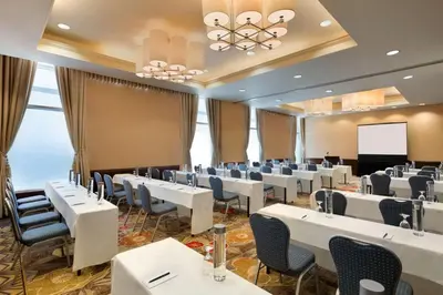 a conference room with tables and chairs and a screen at Embassy Suites Los Angeles Glendale in Glendale