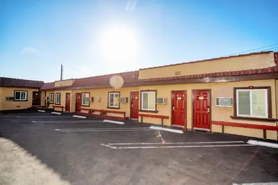 a building with red doors in a parking lot at Geneva Motel in Inglewood