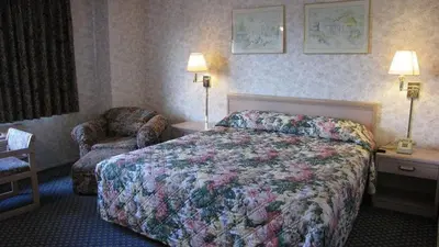 a hotel room with a bed and a chair at Nisei Inn in Gardena